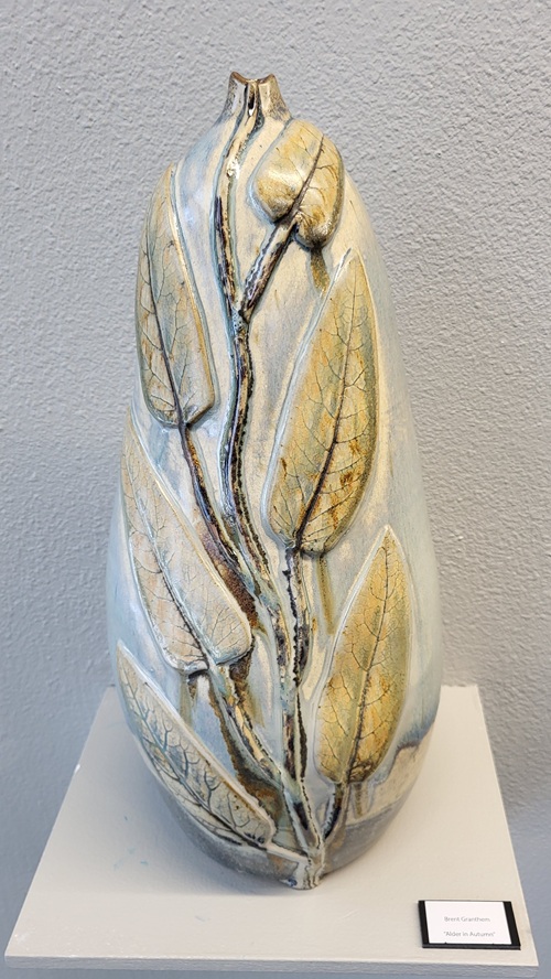 This item is a decorative stoneware pottery vase featuring a hand-carved leaf pattern and variegated blue and gold glazing. A unique, artisan-made piece designed for display. Similar artistic pieces are listed for around $950